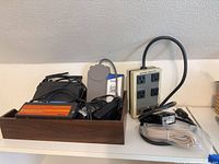 Tray containing Linksys router, cords, Toshiba box, cords beside Surge Sentry unit