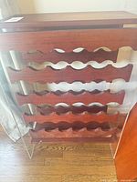 Front view showing entire wooden wine rack with five scalloped tiers and clear acrylic sides