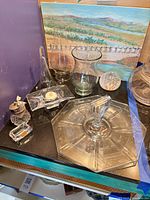 Group shot of all glass items on black surface including tray, vases, paperweight, jar, candleholder, dish