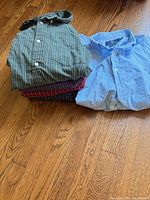 Stack of four folded plaid shirts and separate light blue shirt