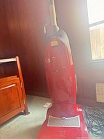 Full view of red upright Miele vacuum standing on floor