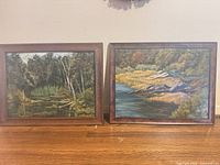Two framed landscape oil paintings side by side