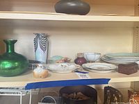 Shelf with bud vases, green vase, assorted porcelain plates and dishes