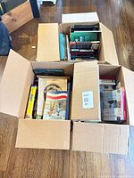 Three open cartons filled with assorted books