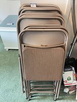 Stack of 11 taupe Samsonite folding chairs showing frames and upholstery