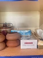 Overall shelf showing stoneware holders, boxed candles, pie server in tray