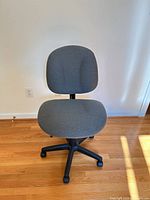 Front view of gray fabric office chair showing seat, backrest and five-caster base