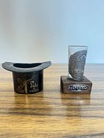 Shot glass on wooden base beside top-hat holder