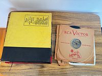 Stack of bound record albums beside loose RCA Victor-sleeved discs