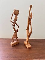 Front view of both carved wooden figurines standing on bases
