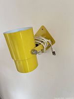 Side view of yellow metal sconce showing cord and mounting plate