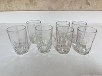 Front view of seven matching clear juice glasses