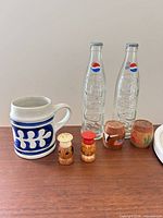 Group view of mug, Pepsi bottles and all four wooden shakers