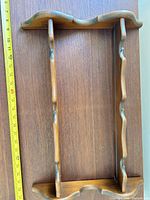 Front view of one spoon rack showing scalloped rails, ruler alongside for scale