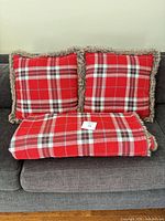 Two plaid pillows and folded matching blanket showing plaid side