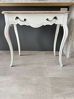 Front view of white French Provincial console table showing cabriole legs and scalloped apron