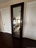 Front view of mirror leaning against wall showing frame and reflective surface