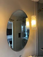 Front view of one oval frameless mirror mounted on wall