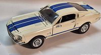 Driver side view of cream Shelby GT 500K model with blue stripes