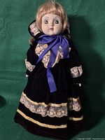 Full view of porcelain doll with dress and stand