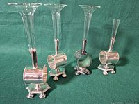 Four silver plate napkin ring bud vases on green background