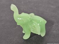 Overall view of small jadeite elephant figurine showing size, color and raised trunk