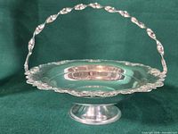 Full view of silver-plated bride’s basket on pedestal with handle raised