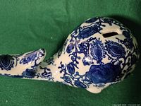 Top and side view of blue and white porcelain whale coin bank showing chinoiserie pattern and coin slot