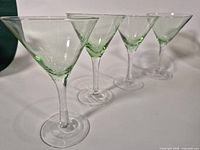 Four pale green martini glasses shown in a row