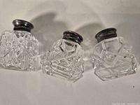 Three cut crystal shakers side by side, view of bodies and sterling collars