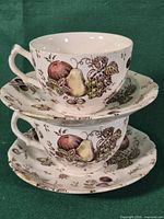 Two stacked teacups each on a saucer showing full pattern