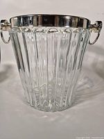 Full view of ribbed glass ice bucket with silver-plated rim and handles