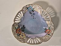Top view of tri-lobed porcelain dish showing floral decals, luster interior, pierced rim