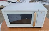 Front view of white microwave with gold handle and dark window