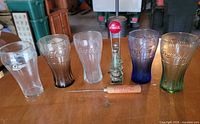 Front view of five Coca-Cola tumblers, salt & pepper shakers in holder, and ice pick
