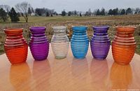 All six coloured ribbed glass vases lined up outdoors