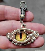 Front view showing glass dragon eye cabochon, wire spirals, bead row, clip