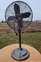 full view of metal pedestal fan on table outdoors