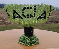 Side view of green beaded pedestal bowl showing overall form and bead pattern