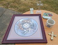 Entire lot on round table showing framed print, crosses, trinket box, crock cup, glass block
