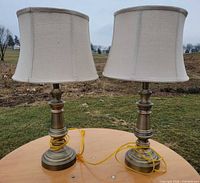 two brass-finish table lamps with shades side by side