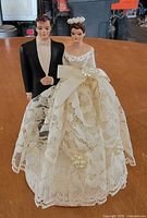Front view of chalkware bride and groom cake topper showing lace gown and faux pearl details