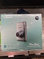 Front of retail box showing Canon PowerShot ELPH 100 HS model and specs