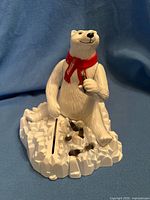 Front view of polar bear mechanical bank showing coin slot and scarf
