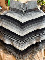 Grey and black knitted cape with fringe detailing
