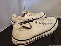 Left side view of both off-white Converse shoes showing canvas uppers and missing laces