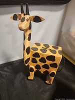 Front and side view of wooden giraffe coin bank showing overall form and painted spots