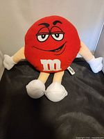 Front view of red M&M plush showing face and limbs