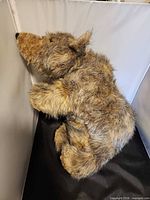 Side view of seated realistic bear plush showing full body and fur texture