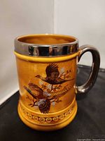 Full view of stein showing pheasant decoration, chrome rim and handle